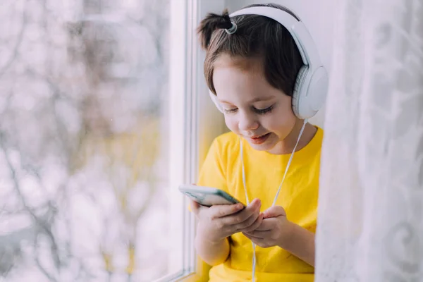 A boy with a phone is sitting on a lifestyle window . Social media. Modern children. An article about developed children. — Zdjęcie stockowe