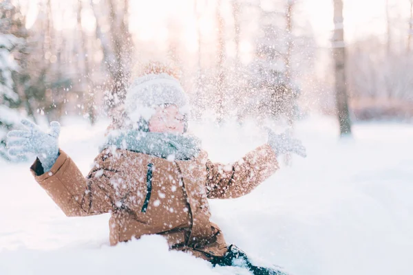 Le garçon jette de la neige dans le mode de vie hivernal. Promenades hivernales. Un article sur les loisirs d'hiver des enfants. — Photo