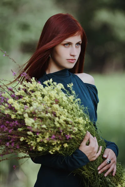 Roodharige meisje met een bouquet van veldbloemen — Stockfoto