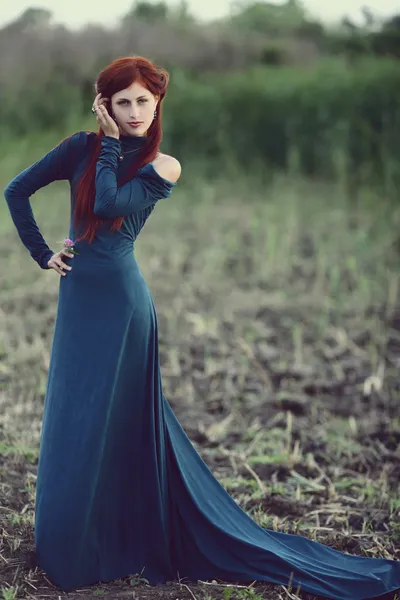 Red-haired girl in a long blue dress in the forest — Stock Photo, Image