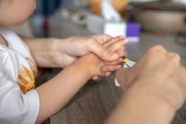 Anne, çocuğun tırnaklarını makasla keser.