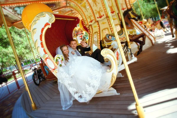 Bela noiva e noivo montando um carrossel — Fotografia de Stock