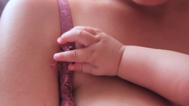 Рукоятка младенца держится за бюстгальтер матери — стоковое видео