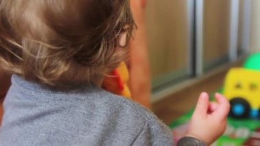 Küçük çocuk oyuncaklarla oynuyor, arkadan bakıyor..