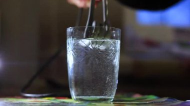 Yaşlı bir kadın eli bir bardak suya metal bir elektrikli şarap kazanını koyar..