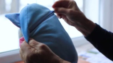 Yaşlı bir kadının kadın elleri, fermuar kilidini çocuk oyuncağının içinde çözer.