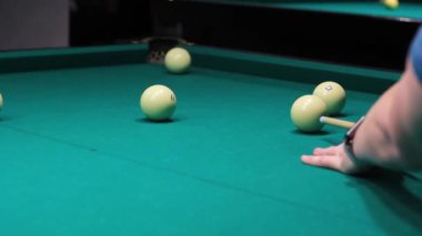 Bir adamın eli bilardo ıstakasıyla topa vuruyor.