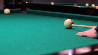 Bir adamın eli bilardo ıstakasıyla topa vuruyor..