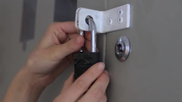 Womans hand opent het slot met een sleutel op het schild close-up. — Stockvideo