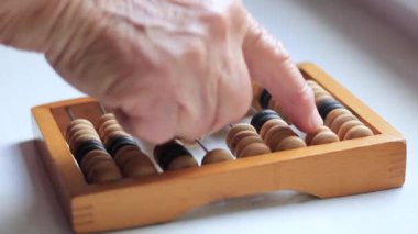 Elderly womans hand counts on vintage abacus.