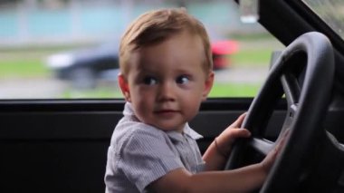 Little boy sitting behind the wheel of a car close-up.