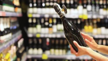 Womens hands choose alcohol, wine in a supermarket.