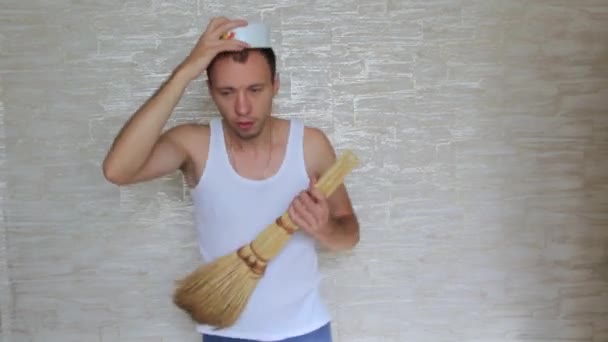 남자는 머리에 접시를 빗자루를 가지고 장난을 있습니다 — 비디오