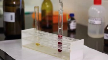 Bir adam su çözeltisini test tüpüne doldurur ve karıştırır.