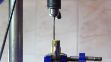 Matkap, mengeneyle tutturulmuş metal bir kilide delik açıyor..