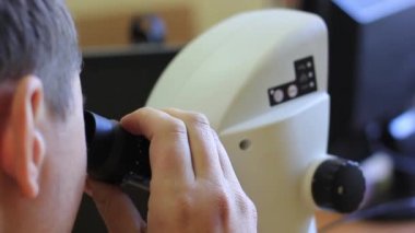 Adam mikroskopa yakından bakıyor..