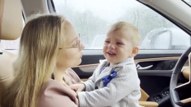 Arabada annesinin kollarında küçük bir çocuk haylazdır, ağlar. Yavaş çekim videosu.