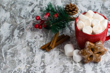 Güzel bir fincanda süt ve marşmelov bulunan lezzetli kahve, zencefilli ekmek, tarçın ve gri arka planda Noel dekoru, fotokopi alanı, üstten manzara.