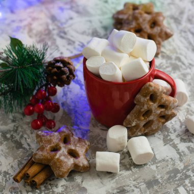 Kokulu zencefilli kurabiyeler, kırmızı bardakta çiğneyen beyaz marşmelov ve açık arkaplan manzaralı yeni yıl dekoru..