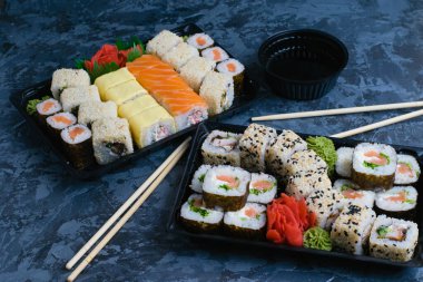 Suşi plastik ambalajda, yiyecek teslimatı konsepti karantina kovid 19 sırasında. Somon, yılan balığı, kırmızı balık, peynir, nori, susam ve pilav, wasabi, zencefil ve soya soslu rulo.