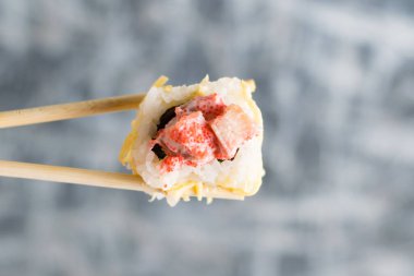 Balık, havyar ve peynirli bambu çubuklu suşi rulosu. İştah açıcı suşi. Fotokopi alanı olan gri tabağa yakın..