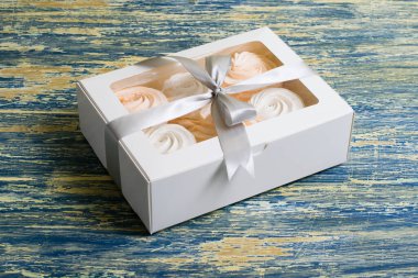 Lezzetli beyaz-pembe şekerlemeler mavi arka planda beyaz bir kutuda.