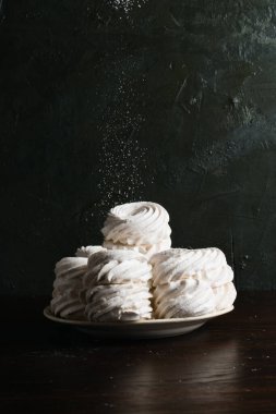 Pudra şekeri serpiştirilmiş bir tabakta bir sürü marşmelov, koyu bir arka planda, metin eklemek için bir yer..