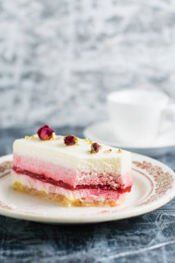 Klasik tabakta tatlı kremalı pasta ve gri arka planda bir fincan kahve.