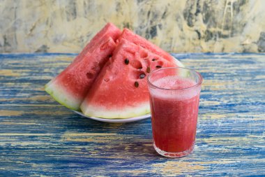 Beyaz tabakta dilimlenmiş tatlı karpuz ve bardakta karpuz püresi.