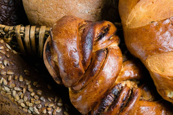 Ассортимент хлеба крупным планом. Сладкая булочка, багет, длинный хлеб, белый и черный хлеб в корзине — стоковое фото