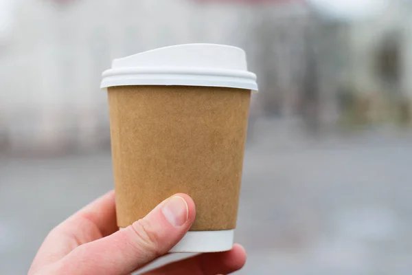 Kaca kopi di tangan close-up di latar belakang kota. Konsep perjalanan turis atau berjalan-jalan di kota — Stok Foto