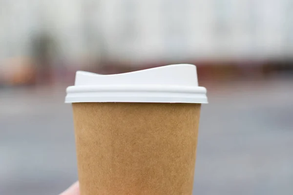 Kaca kopi di tangan close-up di latar belakang kota. Konsep perjalanan turis atau berjalan-jalan di kota — Stok Foto