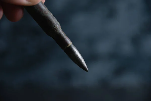 Cartridge in hand close up on dark gray concrete background, copy space. The concept of modern armaments, the war in Ukraine and the defense of the state. — Stock Photo, Image
