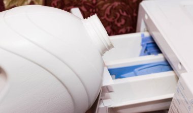 Adam çamaşır makinesinin kompartımanına çamaşır jeli döküyor. Ödev konsepti, çevre koruma ve çevre dostu deterjan kullanımı