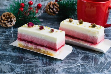 Beyaz sübvansiyonlu leziz kremalı kekler, çay ya da kahve ile kırmızı bardak ve gri arka planda noel dekoru..