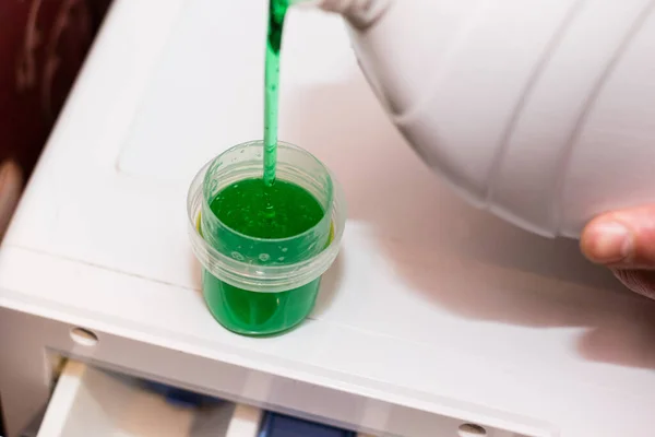 Dispenser with washing gel close up. The person pours gel into the dispenser. The concept of using environmentally friendly detergents.