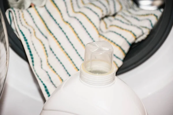 Bottle with washing gel and colorful towels, things in the washing machine.