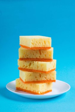 Bulaşık yıkamak ve daireyi temizlemek için süngerler mavi arka planda bir tabakta. Ev için ekolojik deterjan kullanma kavramı.