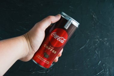 Ukrayna, Chernihiv, 23 Haziran 2022: Koyu gri arka planda bir kadının elinde kola..