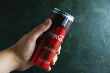 Ukrayna, Chernihiv, 23 Haziran 2022: Koyu gri arka planda bir kadının elinde kola..