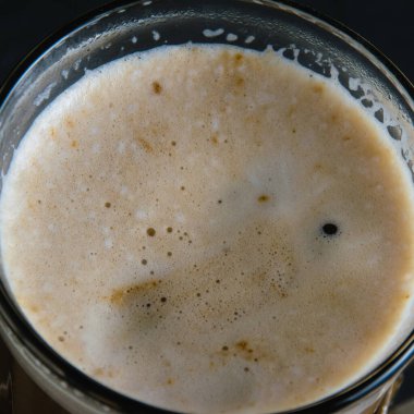 Kahve köpüğü üst manzarayı kapatır. Bardakta kapuçino.