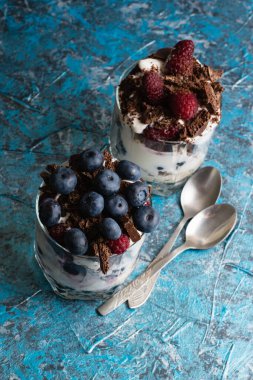 Yabanmersinli tatlılar, yoğurt, çikolata, kiraz, ahududu ve cam bardakta yulaf ezmesi ve fotokopi alanı olan çay kaşıkları..