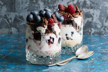 Yabanmersinli tatlılar, yoğurt, çikolata, kiraz, ahududu ve cam bardakta yulaf ezmesi ve fotokopi alanı olan çay kaşıkları..