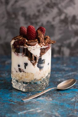 Çikolatalı, yoğurtlu, ahududulu ve arka planda fotokopi alanı olan kaşıklı yulaf ezmeli tatlı..