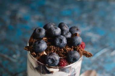 Çikolatalı, yoğurtlu, yaban mersinli ve ahudududulu lezzetli bir tatlı. Arka planda fotokopi alanı olan bir cam bardak.