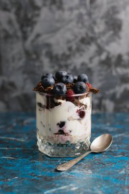 Çikolatalı, yoğurtlu, yaban mersinli ve ahududulu tatlı ve arka planda fotokopi alanı olan bir kaşık..