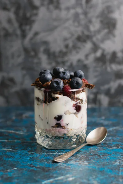 Çikolatalı, yoğurtlu, yaban mersinli ve ahududulu tatlı ve arka planda fotokopi alanı olan bir kaşık..