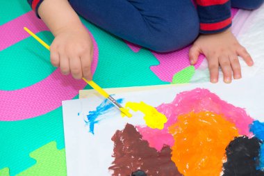 Fırça ve renklerle resim yapan bir çocuğun eli