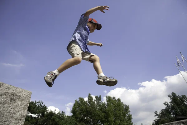 Boy leaps off rock. — Stock Photo, Image
