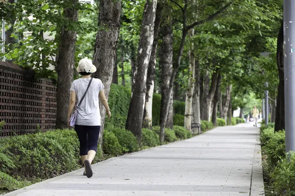 Woman walks along sidewalk. — Stock Photo, Image